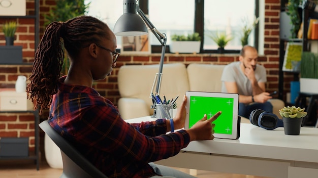 Office manager looking at horizontal greenscreen on digital device, analyzing isolated copy space display and mockup template. Using modern gadget with blank chroma key background.