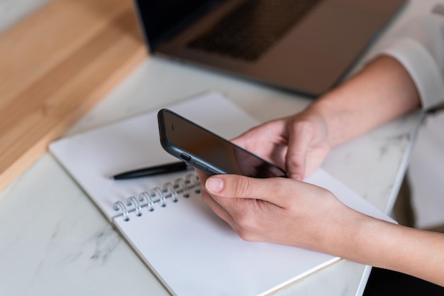 Office manager vrouw met telefoon in handen en notitieboekje op tafel geen gezicht Close-up van vrouwelijke handen met zwarte telefoon op kantoor tafel Bureau Concept van werk