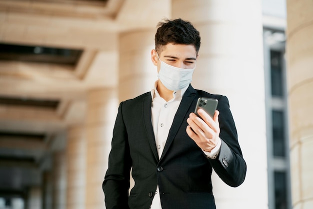 An office manager wearing a coronavirus mask is holding a phone the man is darkhaired