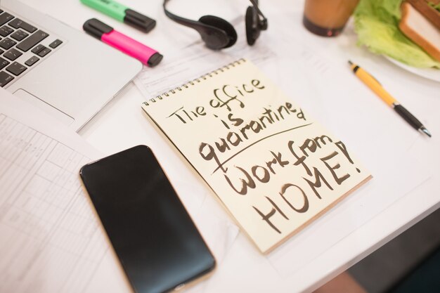 Photo office quarantine work from home inscription on yellow paper in a notebook