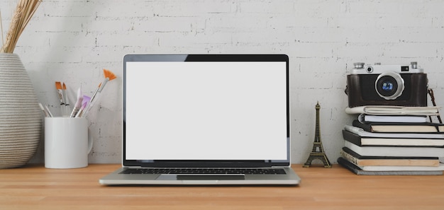 office room with open blank screen laptop computer and office supplies on wooden table