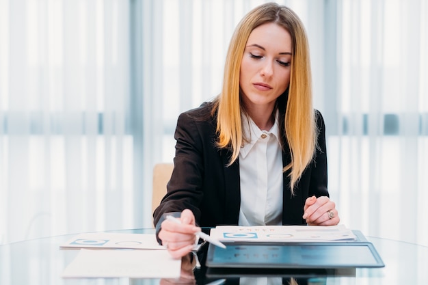 Office routine. Woman working with papers sitting at her desk