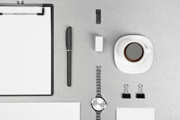 Office set with white sheets of paper cup of coffee watch and stationery on grey background