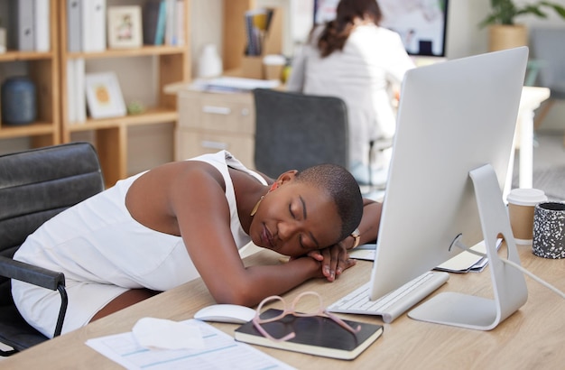 Office sleeping or tired black woman resting on table with burnout is overworked by deadlines at desk Lazy dreaming or exhausted worker with stress or fatigue napping on relaxing break in overtime