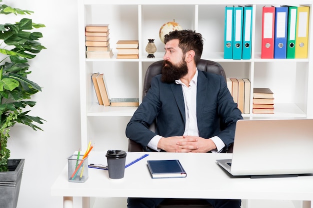 Office staff concept Businessman in charge of business solutions Developing business strategy Risky business Man bearded boss sit with laptop Manager solving business problems Office routine