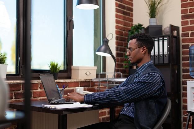 사무실 시작 직원이 화면을 보고 있는 시장 조사 원형 차트에서 작업하는 노트북에 입력합니다. 기업가는 책상에 앉아 비즈니스 판매 데이터를 분석하기 위해 휴대용 컴퓨터를 사용합니다.