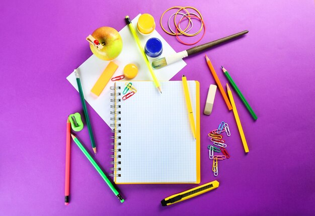 Офисные и студенческие инструменты на фиолетовом фоне крупным планом