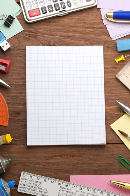 Office supplies and checked notebook on wood background