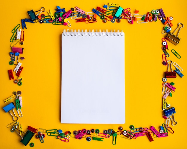 Office supplies of colored buttons and paper clips with empty note pad