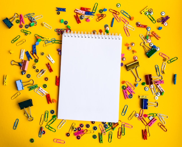 Office supplies of colored buttons and paper clips with empty note pad