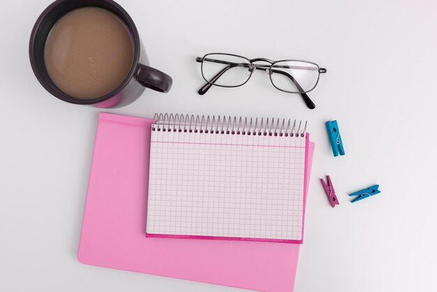 Office supplies over desk with keyboard and glasses and coffee
cup for working remotely assorted school utilities for studying
with hot drink and eyeglasses