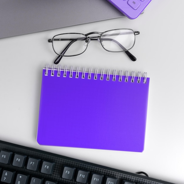 Office supplies over desk with keyboard and glasses and coffee
cup for working remotely assorted school utilities for studying
with hot drink and eyeglasses