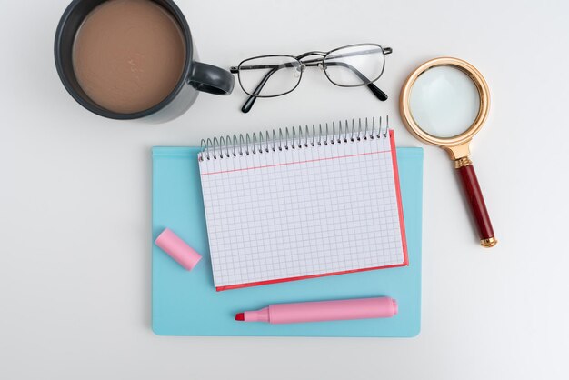 Office supplies over desk with keyboard and glasses and coffee
cup for working remotely assorted school utilities for studying
with hot drink and eyeglasses