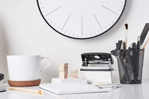 Office supplies and wall clock on white