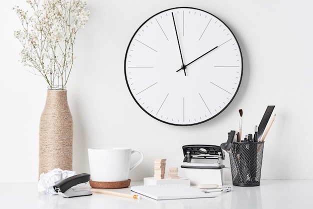 Office supplies and wall clock on white