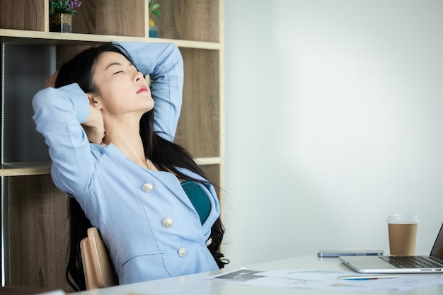 オフィス症候群若いアジアの女性実業家がコンピューターのラップトップで作業した後に首に痛みを感じる疲れた女性の首が緊張した筋肉が疲れたコンピューターの仕事が関節の肩の背中の痛みを痛める
