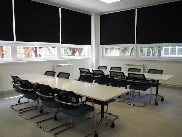 Office table and chairs in the interior Black blinds for darkening the room Modern interior design