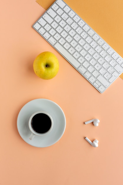 Office table desk with keyboard, apple, earphones and coffee cup