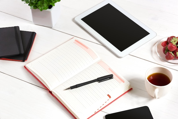 Photo office table desk with set of supplies white blank notepad cup pen tablet flower on white background...