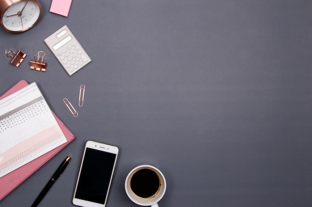 Office table desk with smartphone and other office supplies on grey background.