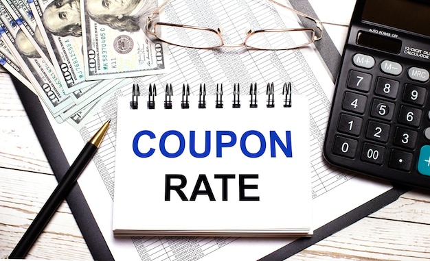 사무실 테이블에는 COUPON RATE 안경과 달러라는 텍스트가 있는 계산기 펜 노트북이 있습니다. 세련된 직장 비즈니스 개념