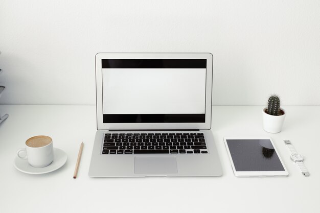 office table on which laptop, coffee, tablet, camera and other items