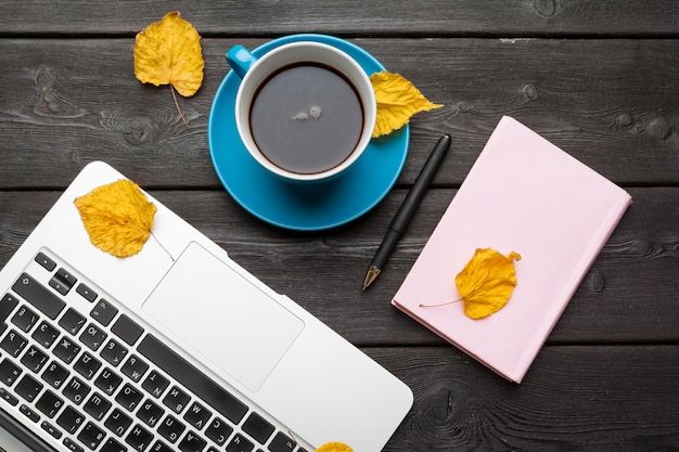 Office table with blank notebook and laptop / Coffee cup