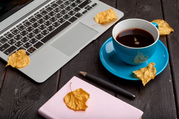 Office table with blank notebook and laptop / Coffee cup