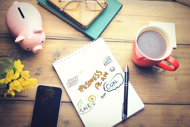 Office table with a coffee cup, a plan on notepad