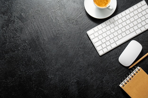 Office table with cup of coffee, keyboard and notepad