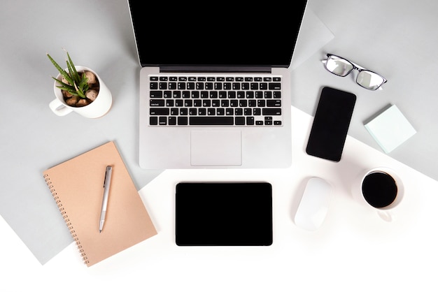 Office table with laptop computer, notebook, digital tablet and mobile phone on two tone b