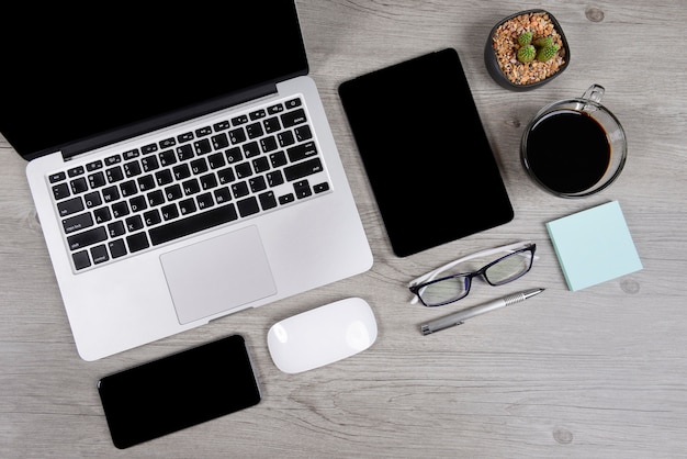 Office table with laptop computer, notebook, digital tablet, and smartphone on wood backgr