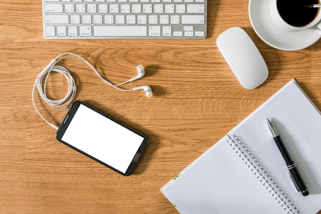 Office table with notepad, computer, coffee cup, computer mouse , pen , smartphone , headphone