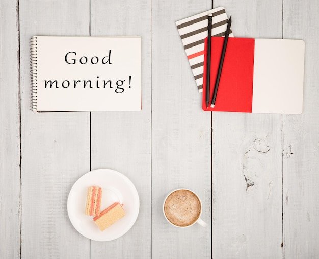 Foto tavolo da ufficio con blocco note e testo buongiorno tazza di caffè e cialde