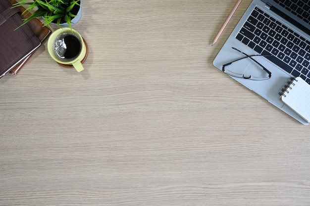 Office tafel bovenaanzicht houten tafel met laptop, glazen, koffie en kantoorbenodigdheden.