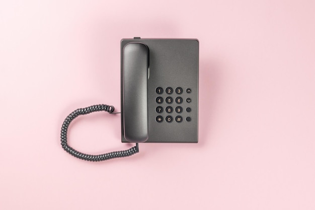 The office telephone is gray on a pink background Flat lay