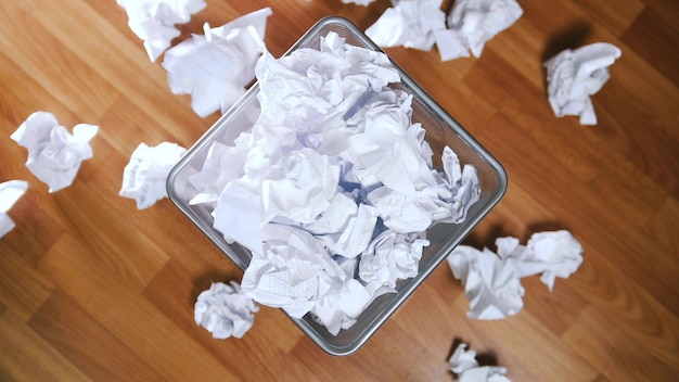 An office trash basket filled up with paper