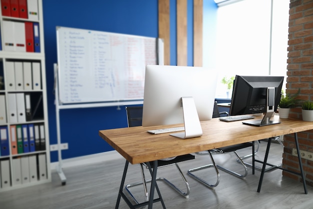 An office in which desk is computers white information board and cabinet with documents. Workspace planning in office concept