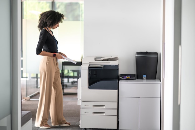 Photo office .woman in balck shirt and beige pants in the office looking determined