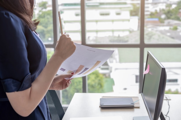 Office woman is standing watching the document file