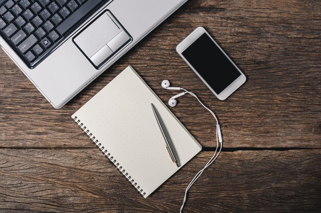 office wooden desk with pen, notepad, coffee cup, smartphone and earphones