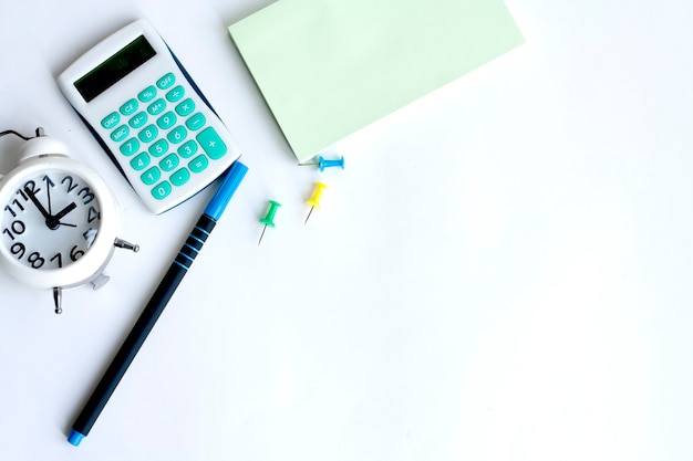 Office work, clock, calculator, note paper, paper clips, pen and coffee on white background, copy space