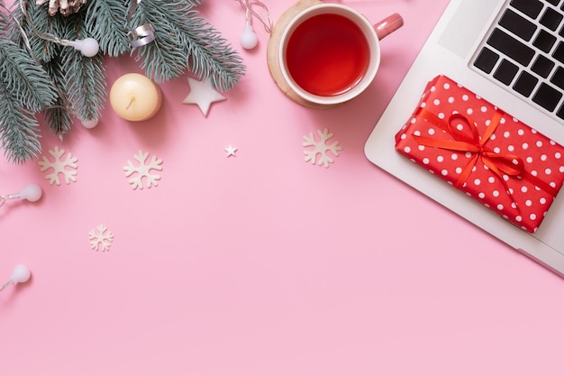 Офисный рабочий стол с рождественским и новогодним украшением, вид сверху, плоский, лежал на розовом фоне. Скопируйте место для текста во время зимних каникул.
