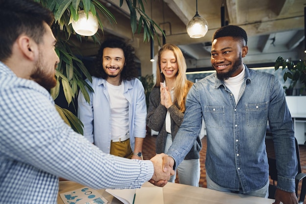 Photo office work team greeting their new african american male employee