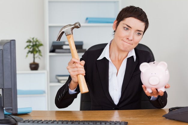 Office worker breaking a piggybank with a hammer