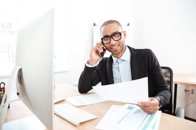 Office worker calling on the phone and reading business document in the office