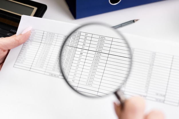 Photo an office worker examines documents through a magnifying glass