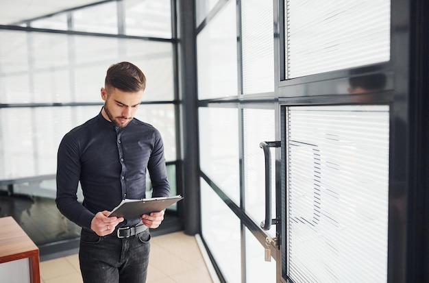 Office worker in formal clothes standing indoors at daytime.