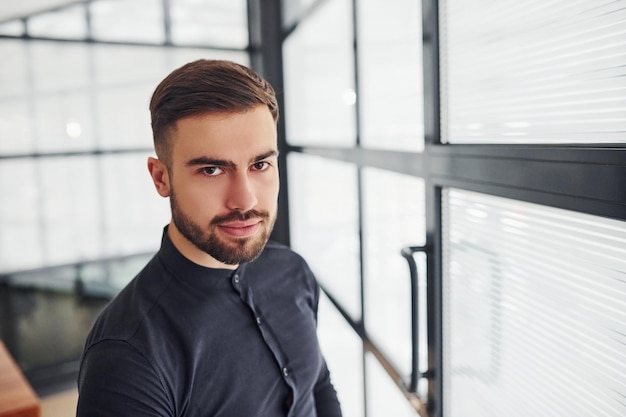 Office worker in formal clothes standing indoors at daytime.