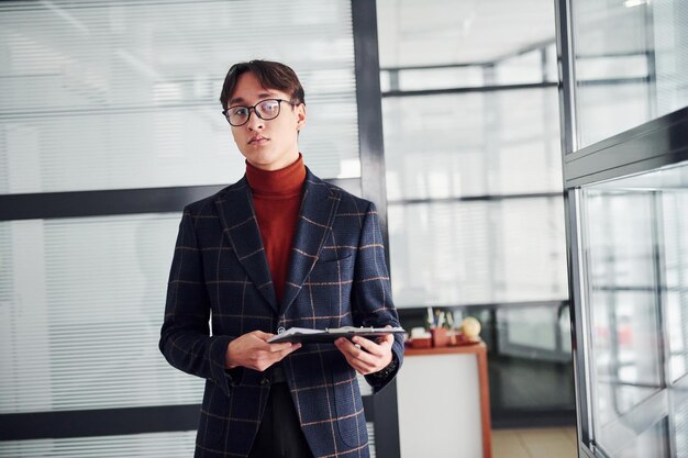 Office worker in glasses and in formal clothes standing indoors.